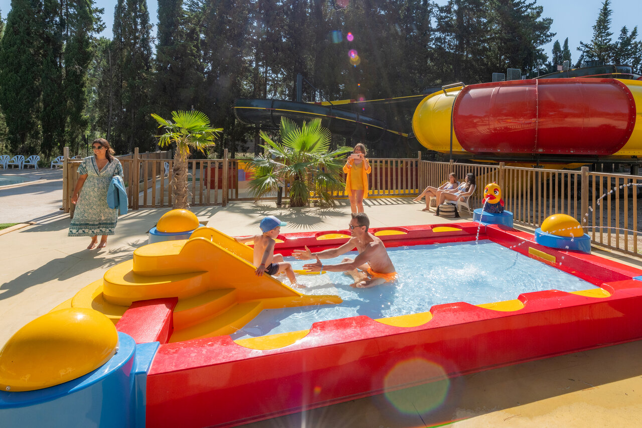 Kleurrijk kinderbad met glijbaan, vader en kind, op camping CAPFUN Or in La Grande Motte (34).