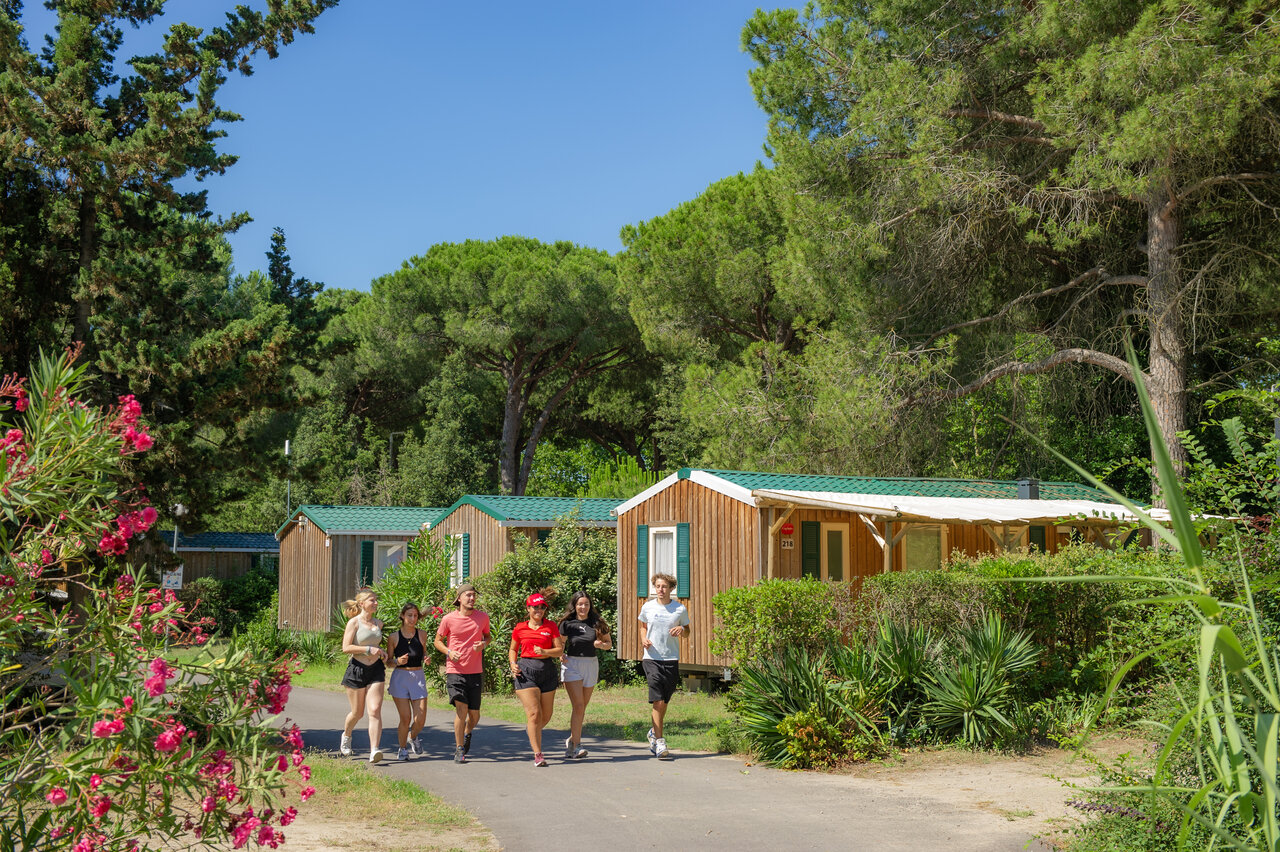 Jonge joggers en houten mobile homes op camping CAPFUN Or, La Grande Motte (34).