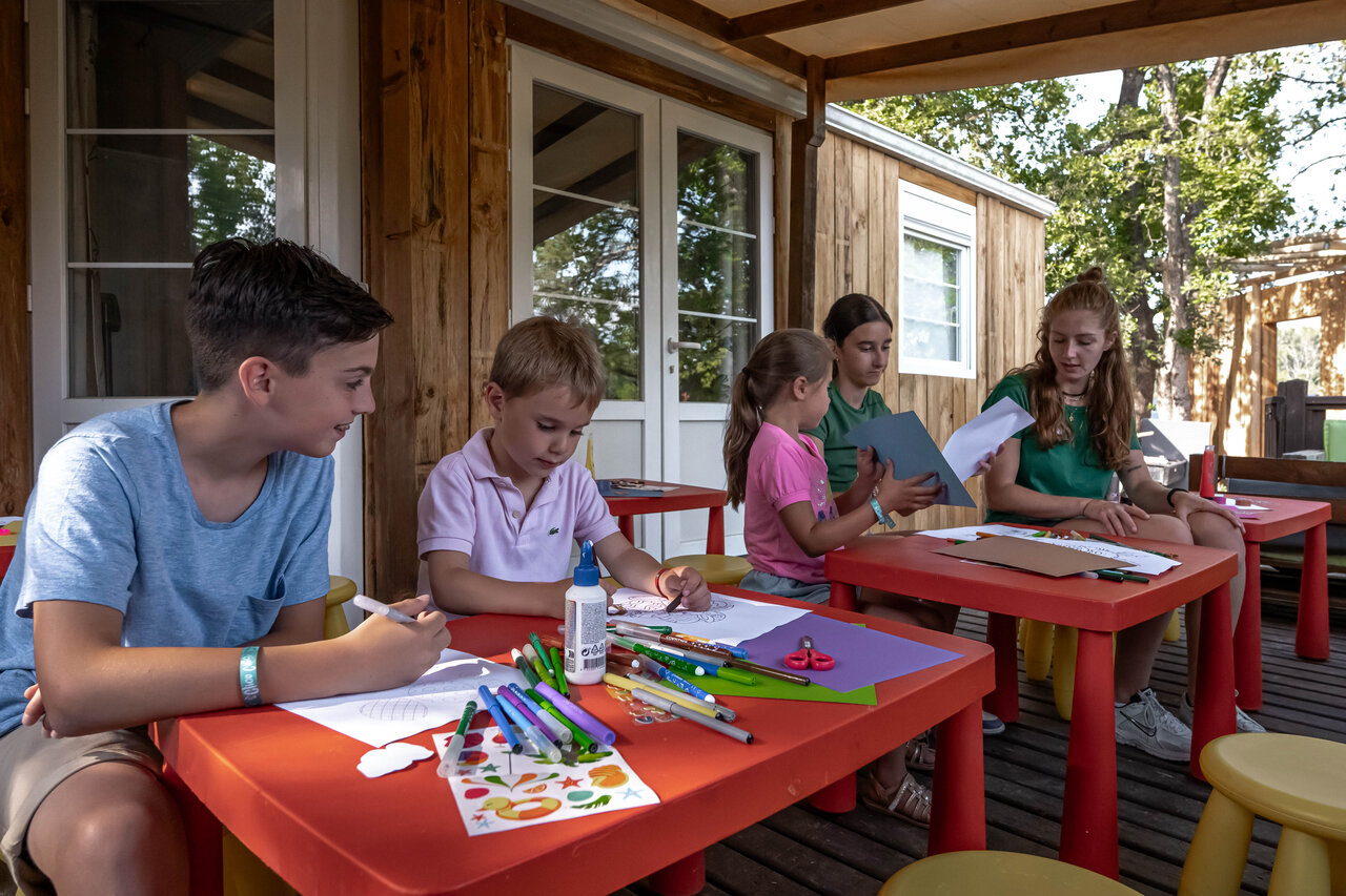 Kinderen bezig met creatieve workshop op Mobil-home terras op camping CLICOCHIC Or�e d'Azur in OPIO (06).