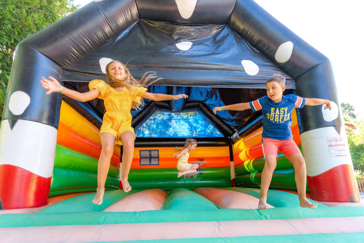 Kinderen springen op kleurrijk springkasteel op camping CAPFUN Oursi�re in Villard de Lans (38).