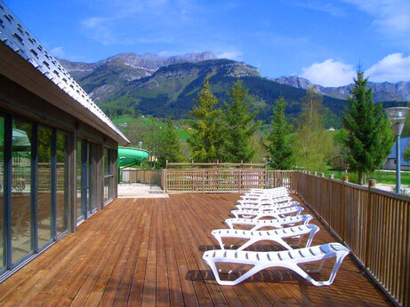 Houten terras, stoelen, waterglijbaan op camping CAPFUN Oursi�re in Villard de Lans.