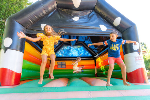 Kinderen springen vrolijk op een kleurrijk springkasteel op camping CAPFUN Oursière in Villard de Lans (38).