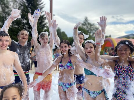 Lachende kinderen en tieners genieten van een schuimfeest op camping CAPFUN Oursière in Villard de Lans (38).