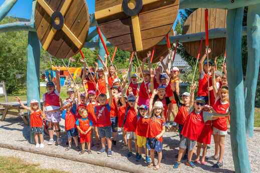 Lachende kinderen spelend op houten speeltoestel op camping CAPFUN Oursière in Villard de Lans (38).
