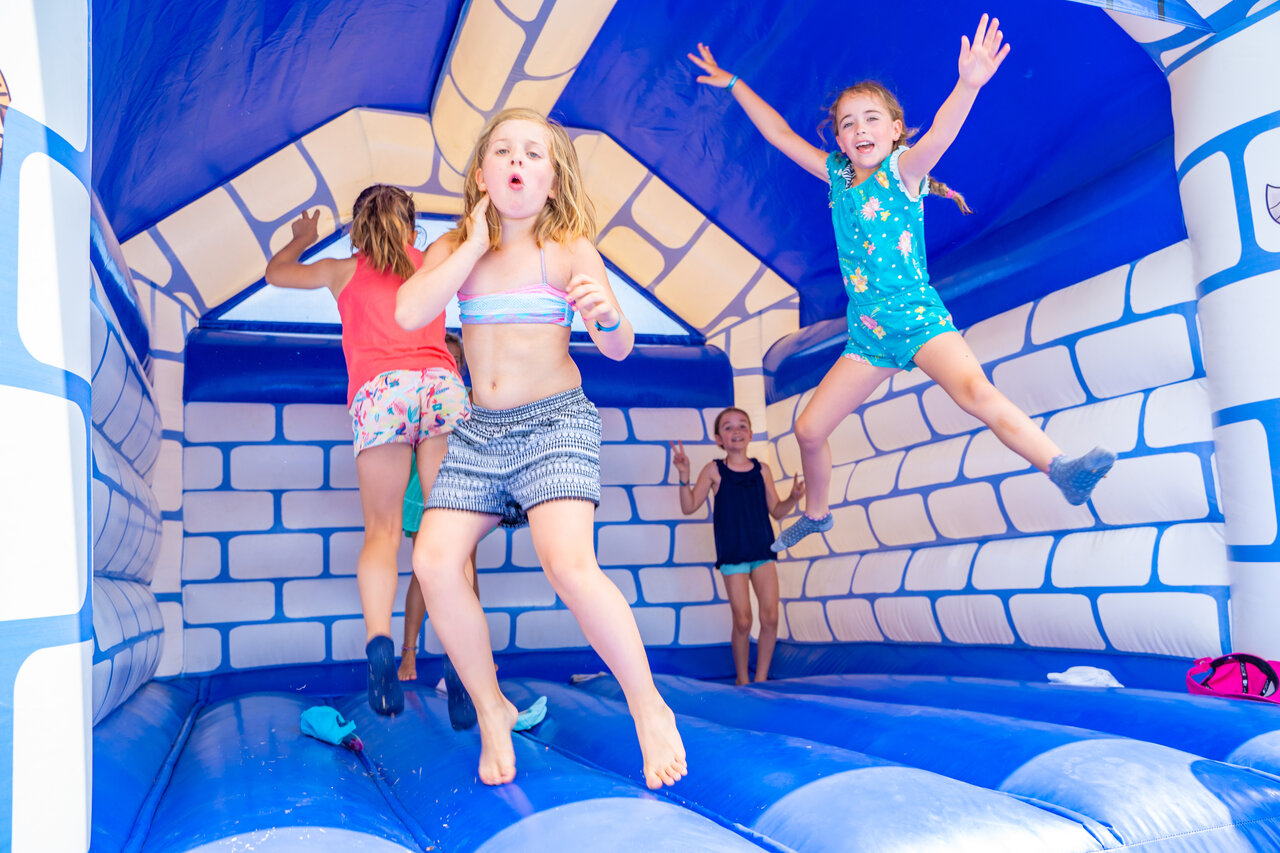 Kinderen springen in een blauw-wit springkasteel op camping CAPFUN Pachacaid in La Mole (83).