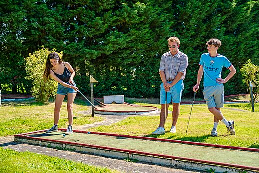 Jongeren spelen minigolf op een groene baan op camping CAPFUN Pachy in FOSSES LA VILLE.