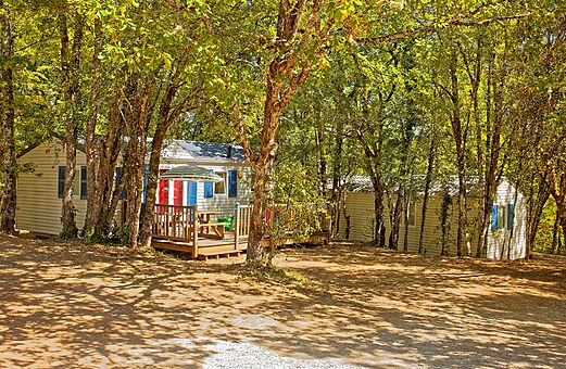 Schaduwrijke stacaravan met houten terras op camping VAGUES OCEANES Paille Basse.
