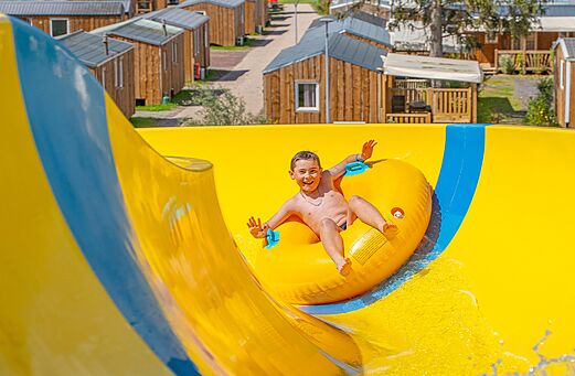 Gele waterglijbaan met kind op camping CAPFUN Palais de Gaufrette (57).