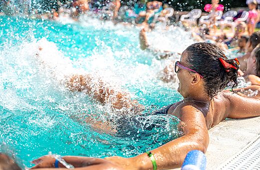 Buitenzwembad met waterstralen en zwemmers op camping CAPFUN Palais de Gaufrette (57).