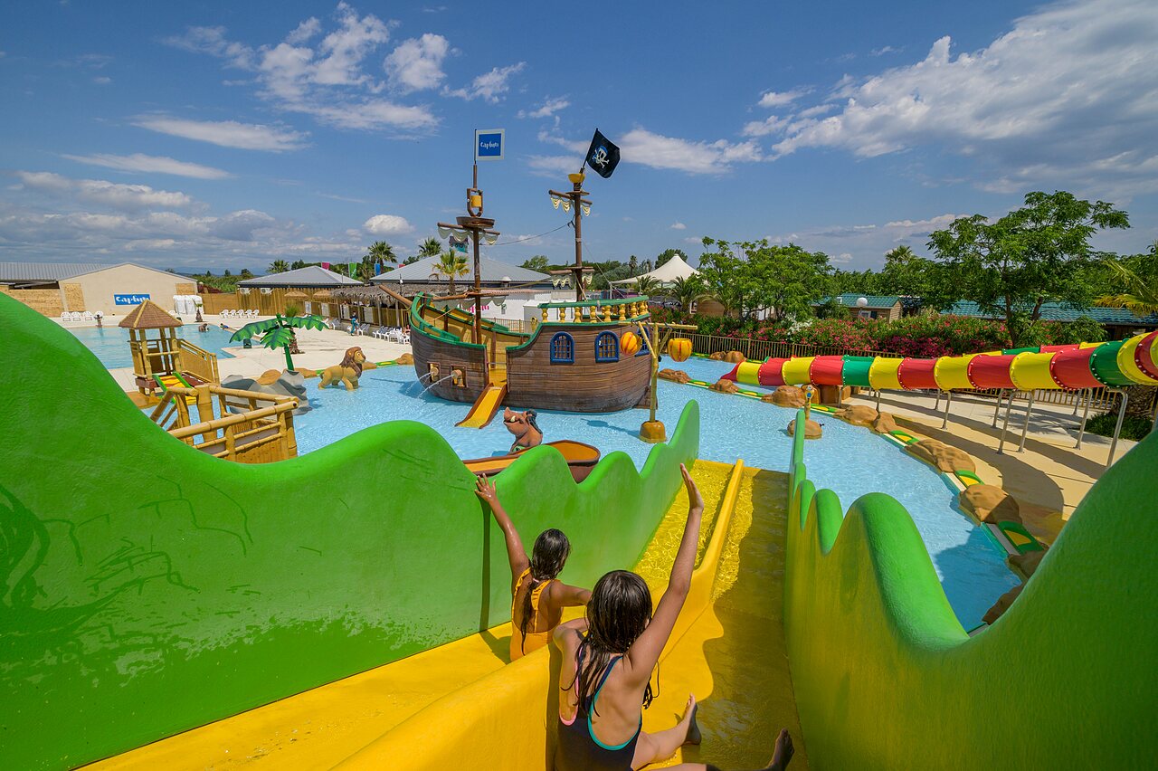 Waterpark met glijbanen, piratenschip en kinderen op camping CLICOCHIC Palmira Beach in Vendres-Plage (34).