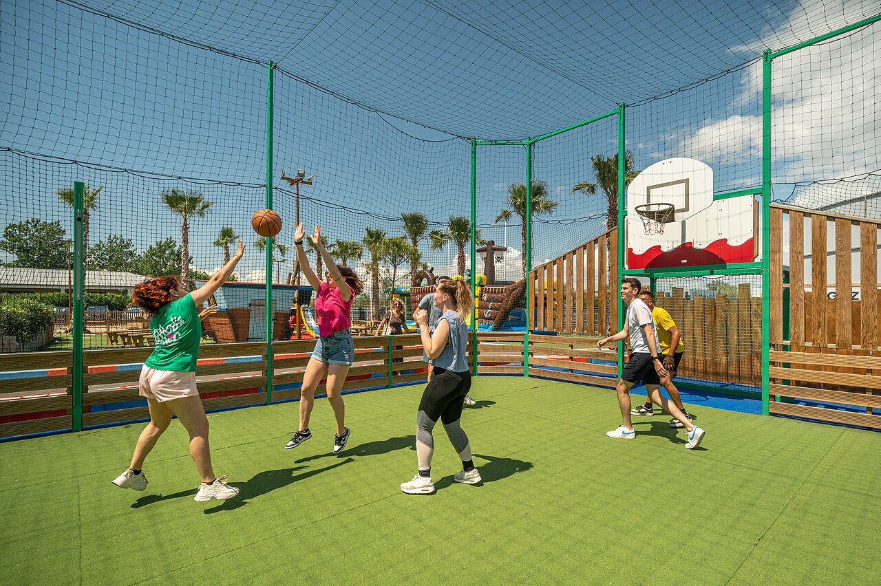 Jongeren basketballen op omheind multisportterrein op camping CLICOCHIC Palmira Beach in Vendres-Plage (34).