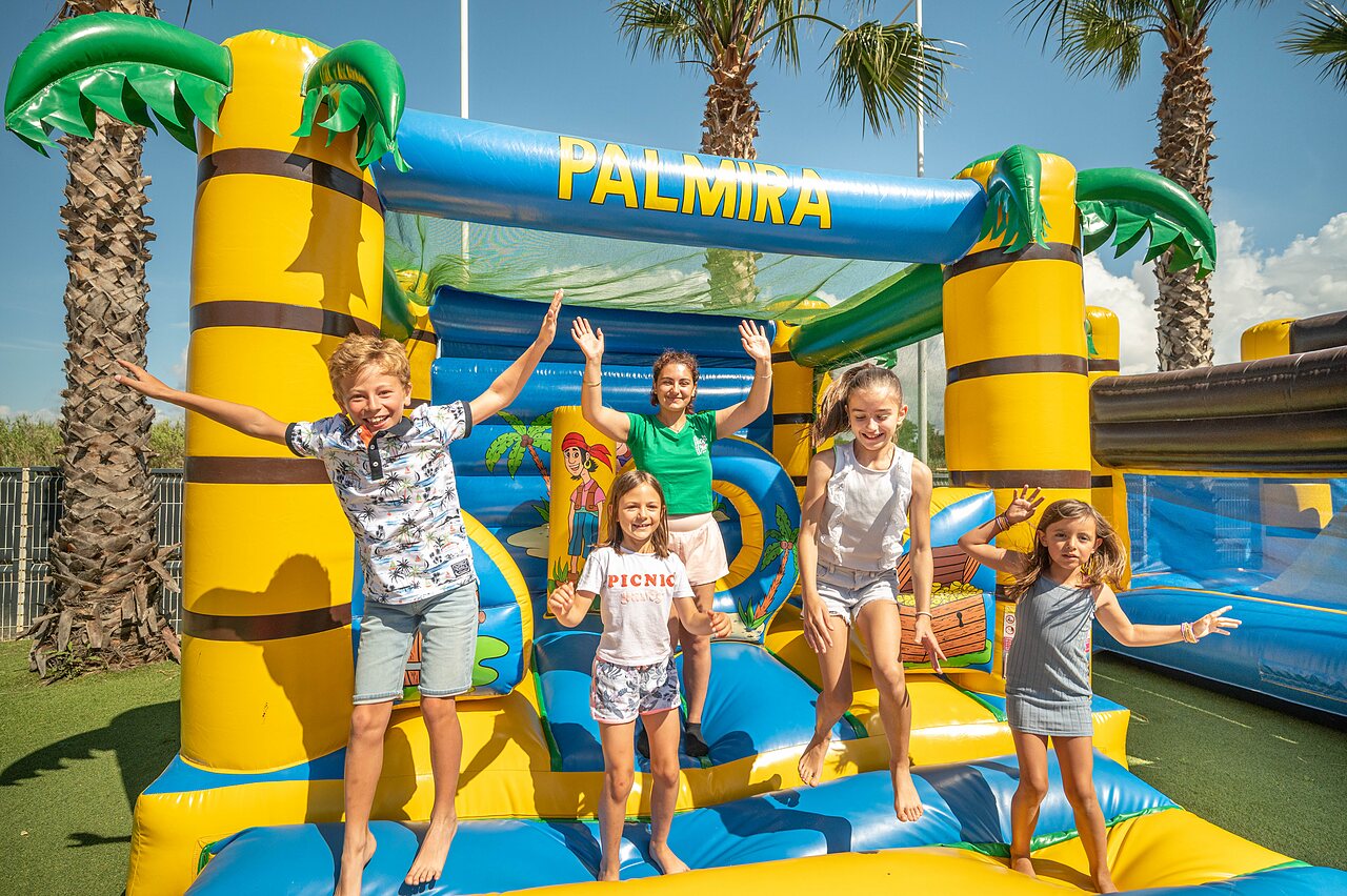 Vrolijke kinderen springen op opblaasbare structuur PALMIRA op camping CLICOCHIC Palmira Beach in Vendres-Plage (34).