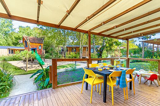 Overdekt terras met eettafel en speeltuin op camping CAPFUN Paradis de Bazas in BAZAS (33).
