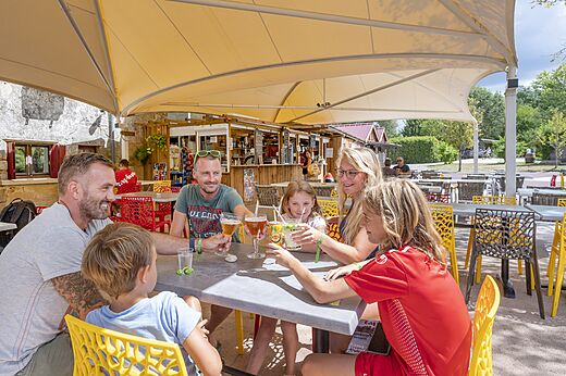 Lachende familie proost aan de bar van CAPFUN Paradis de Bazas (33).