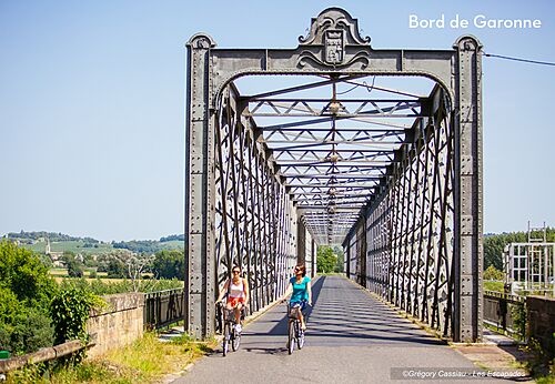 Twee personen fietsen over metalen brug nabij de Garonne, Bazas.