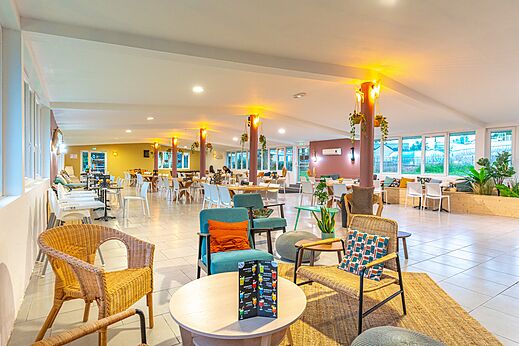Moderne bar- en restaurantruimte met tafels en stoelen op camping CAPFUN Parc de Paris in Villevaudé (77).