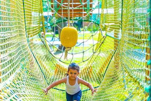 Kind in nettunnel van de speeltuin op camping CAPFUN Parc de Paris in Villevaudé.
