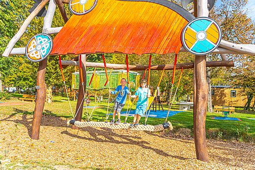 Lachende kinderen op een reuzenschommel van touw op camping CAPFUN Parc de Paris in Villevaudé (77).