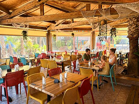 Familierestaurant met kleurrijke tafels op camping CAPFUN Paris Roussillon in ARGELES SUR MER (66).