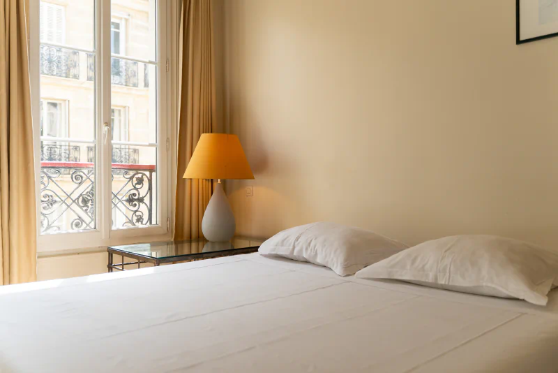 Comfortabele tweepersoonskamer met wit bed en raam, op camping CAPFUN Hotel Paris Saint Germain in PARIJS (75).