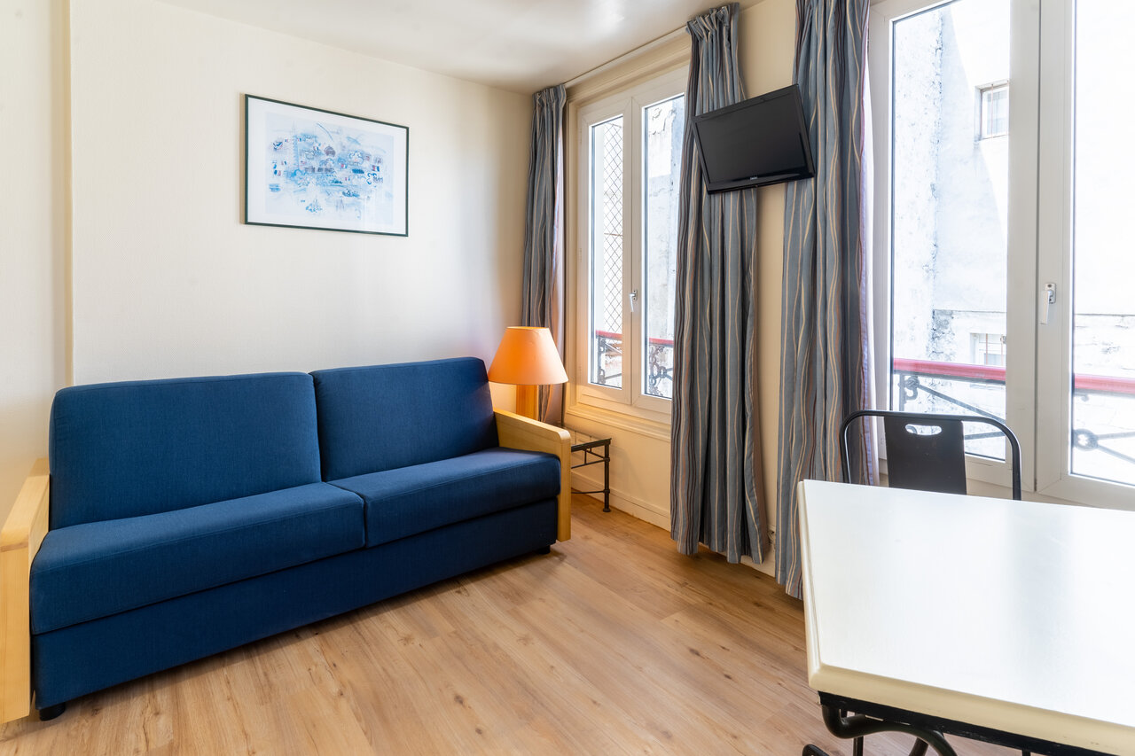 Slaapbank, wand-tv en eethoek in accommodatie op camping CAPFUN Hotel Paris Saint Germain in PARIJS (75).