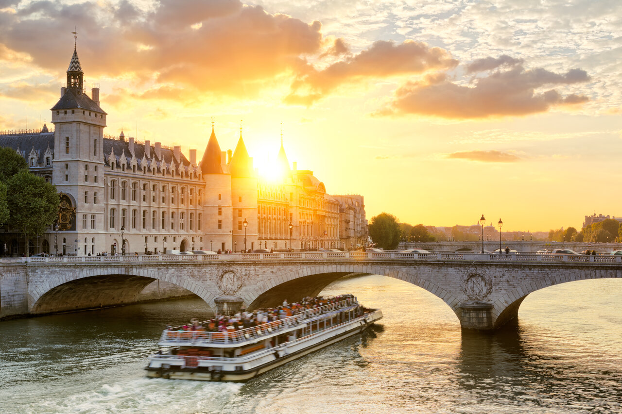 Toeristenboot op de Seine, Conciergerie en Pont Neuf, zonsondergang in Parijs.