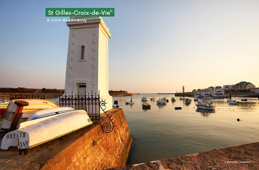 Haven van Saint-Gilles-Croix-de-Vie met boten en vuurtoren bij zonsondergang.