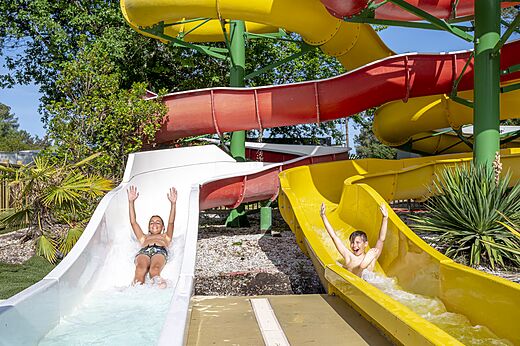 Vrolijke kinderen op kleurrijke waterglijbanen op camping CAPFUN Pinèda in CAZAUX (33).