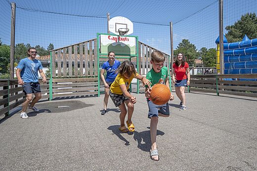 Multisportterrein met kinderen die basketballen op camping CAPFUN Pinèda in CAZAUX (33).