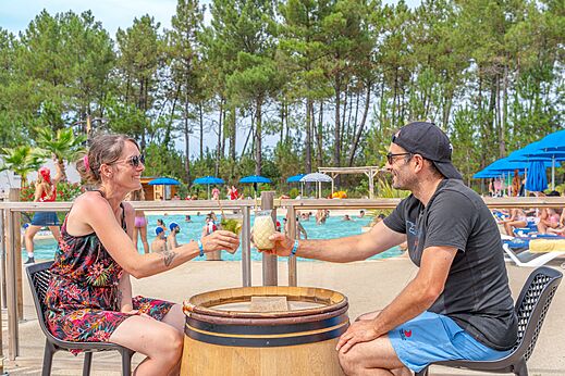Lachend stel drinkt een drankje aan de bar bij het zwembad op camping CAPFUN Pinèda in CAZAUX (33).