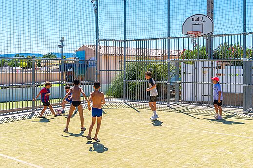 Kinderen spelen voetbal en basketbal op multisportterrein bij camping CAPFUN La Pin�de de Grimaud.