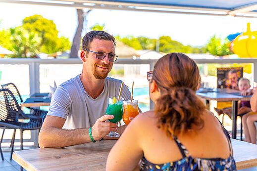 Stel geniet van cocktails aan de bar van camping CAPFUN La Pin�de de Grimaud.