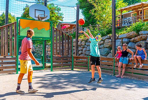 Basketbalveld met jongeren op camping CAPFUN Plantas in SAINT VINCENT DE DURFORT (07).