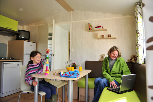 Interieur van stacaravan, kind speelt en vrouw bij CAPFUN Plan du Fernuy.