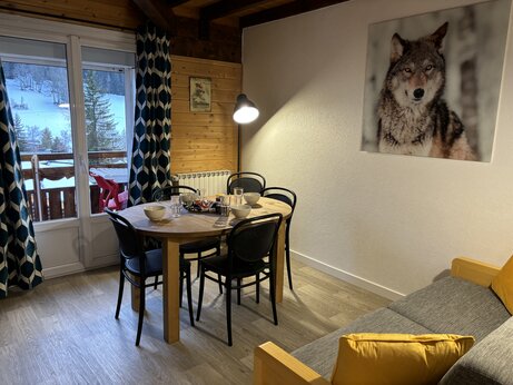 Interieur Mobil-home met eettafel en besneeuwd bergzicht op camping CAPFUN Plan du Fernuy in LA CLUSAZ (74).