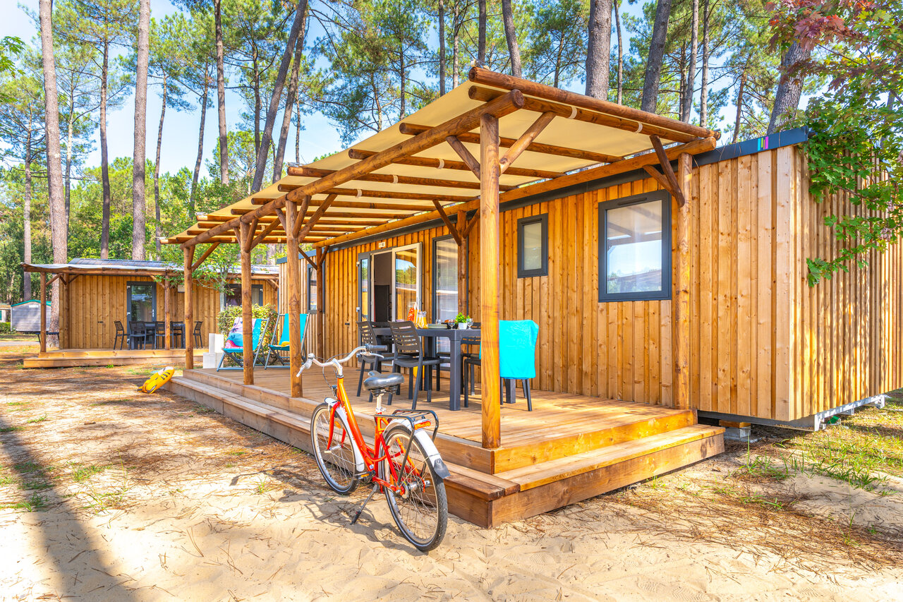 Houten stacaravan met overdekt terras en fiets, op camping CAPFUN Pomme de Pin in Saubion (40).