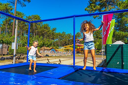 Kinderen springen op reuzentrampoline op camping CAPFUN Pomme de Pin Saubion.