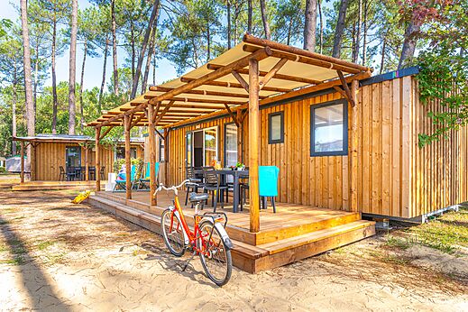 Moderne stacaravan met overdekt terras en fiets op camping CAPFUN Pomme de Pin in Saubion (40).