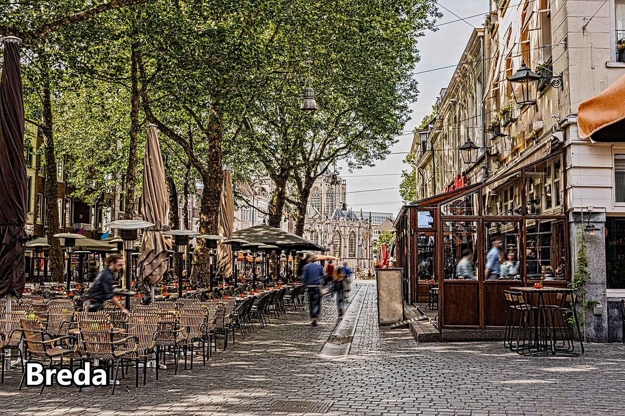 Levendige straat met terrassen en historisch gebouw in Breda, Nederland.