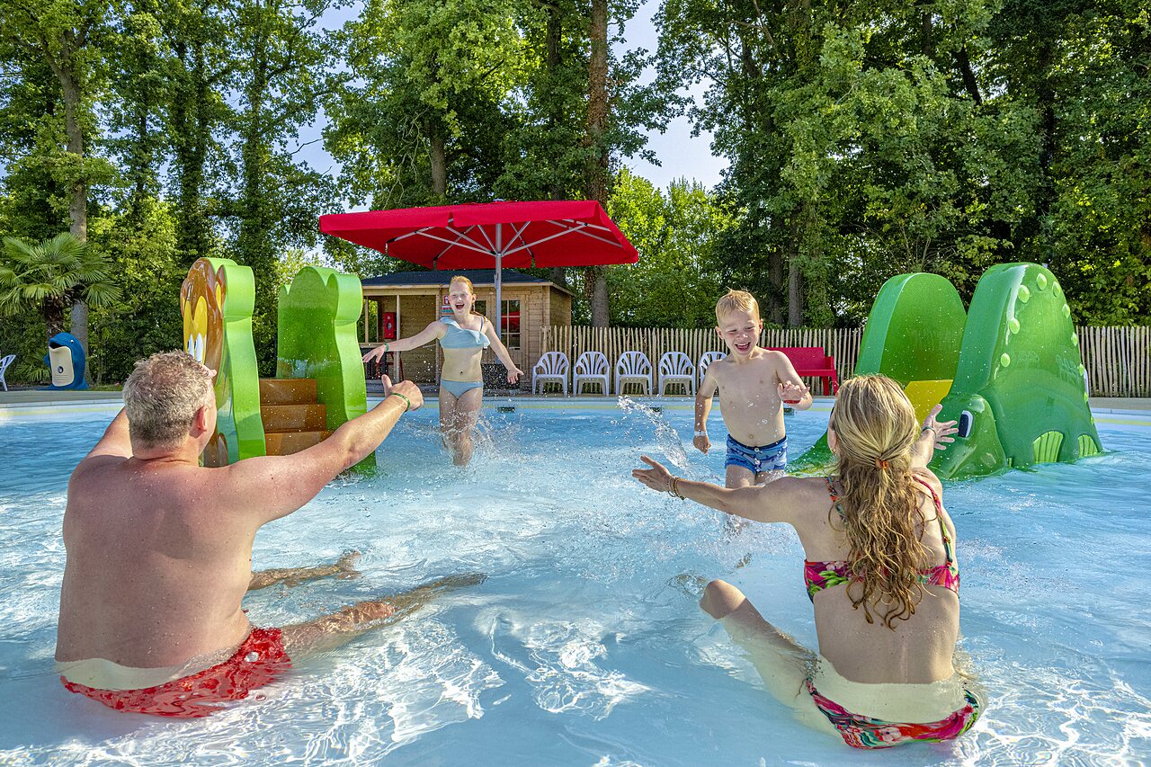 Familie plezier in zwembad met waterspellen op camping CAPFUN Ponderosa in Ulicoten.