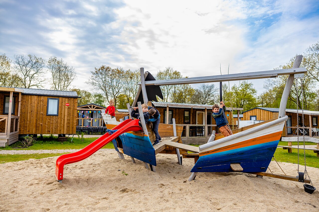 Kinderen spelen op bootvormige speeltuin met glijbaan op camping CAPFUN Ponderosa in Ulicoten.