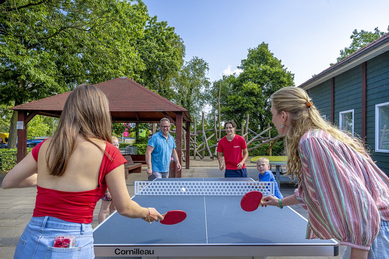 Familie speelt tafeltennis buiten op camping CAPFUN Ponderosa in Ulicoten.
