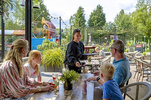 Familie genietend van het buitenrestaurant op camping CAPFUN Ponderosa in Ulicoten.