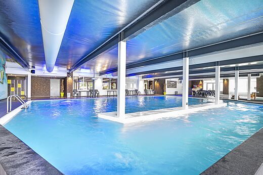 Verwarmd binnenzwembad met blauwe verlichting op camping CAPFUN Ponderosa in Ulicoten.