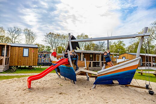 Speeltuin boot, glijbaan en kinderen op camping CAPFUN Ponderosa in Ulicoten.