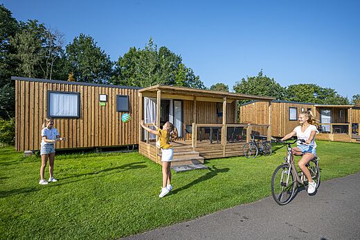 Houten stacaravans met terras en spelende kinderen op camping CAPFUN Ponderosa in Ulicoten.