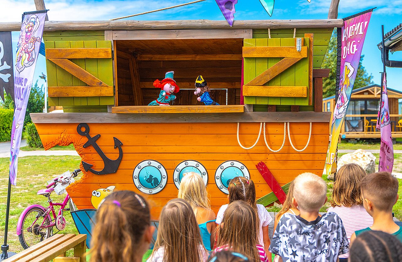 Kinderen kijken poppenkastvoorstelling op bootpodium op camping VAGUES OCEANES in Gouaix.