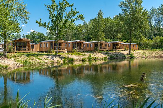 Houten stacaravans aan een vijver, op camping VAGUES OCEANES Près de la Fontaine à Gouaix (77).