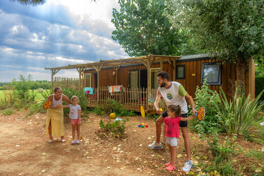 Familie speelt voor een Mobil-home met terras op camping CAPFUN Prises in La TRANCHE SUR MER (85).