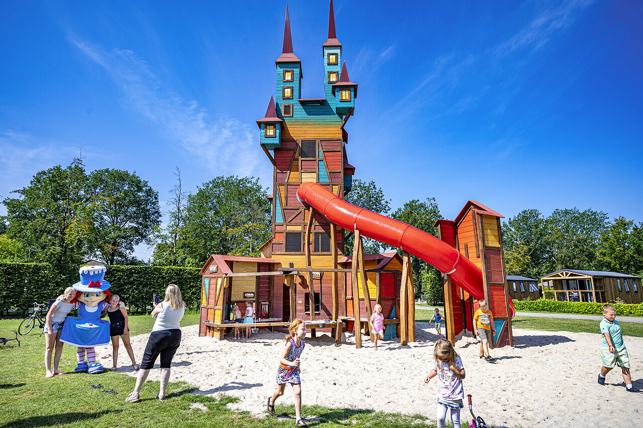 Kleurrijk speelkasteel met glijbaan en kinderen op camping CAPFUN Rakelbos in Westelbeers.